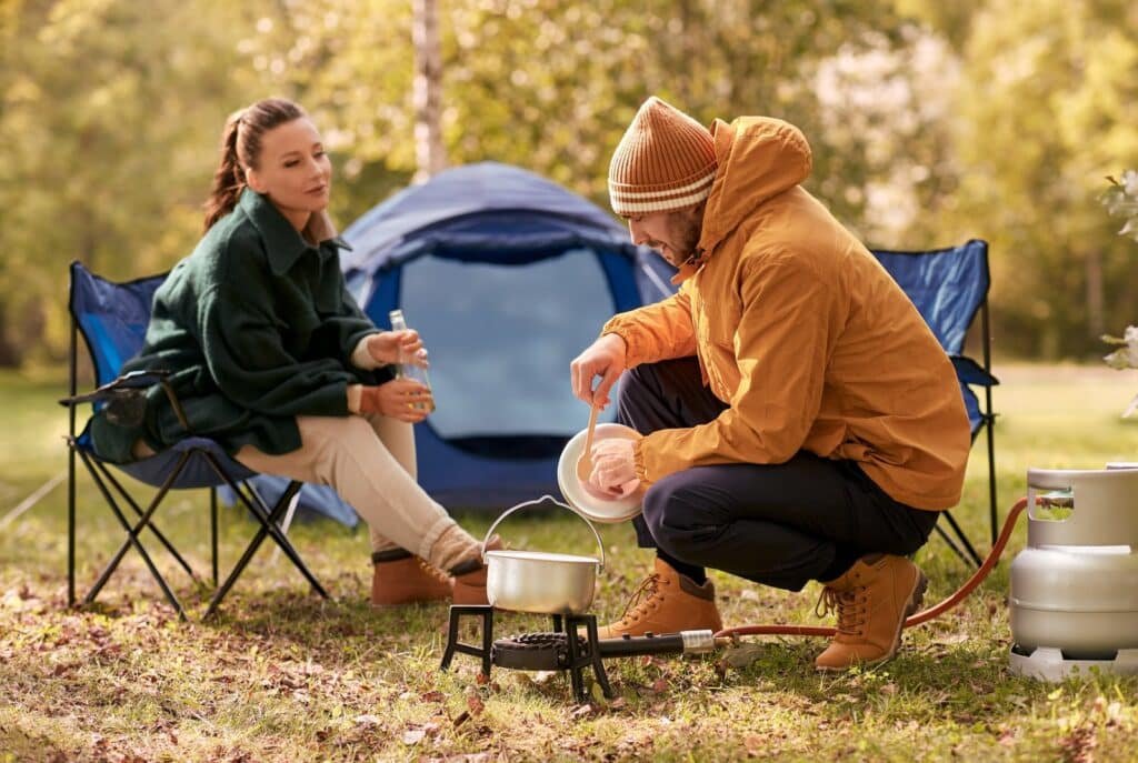 Couple cooking food at tent camping place Couple cooking food at tent camping place