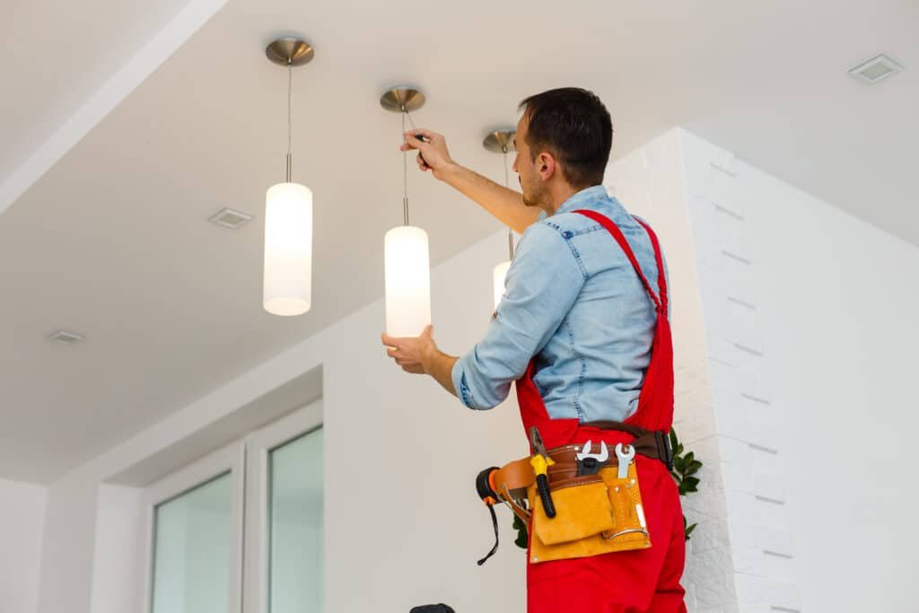 Electrician man worker installing ceiling light