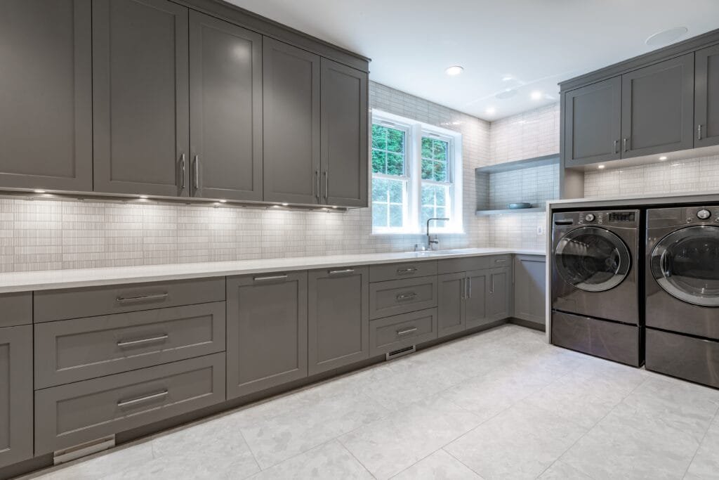 Large laundry room with long counter grey cabinets and under cabinet lighting Large laundry room with long counter grey cabinets and under cabinet lighting