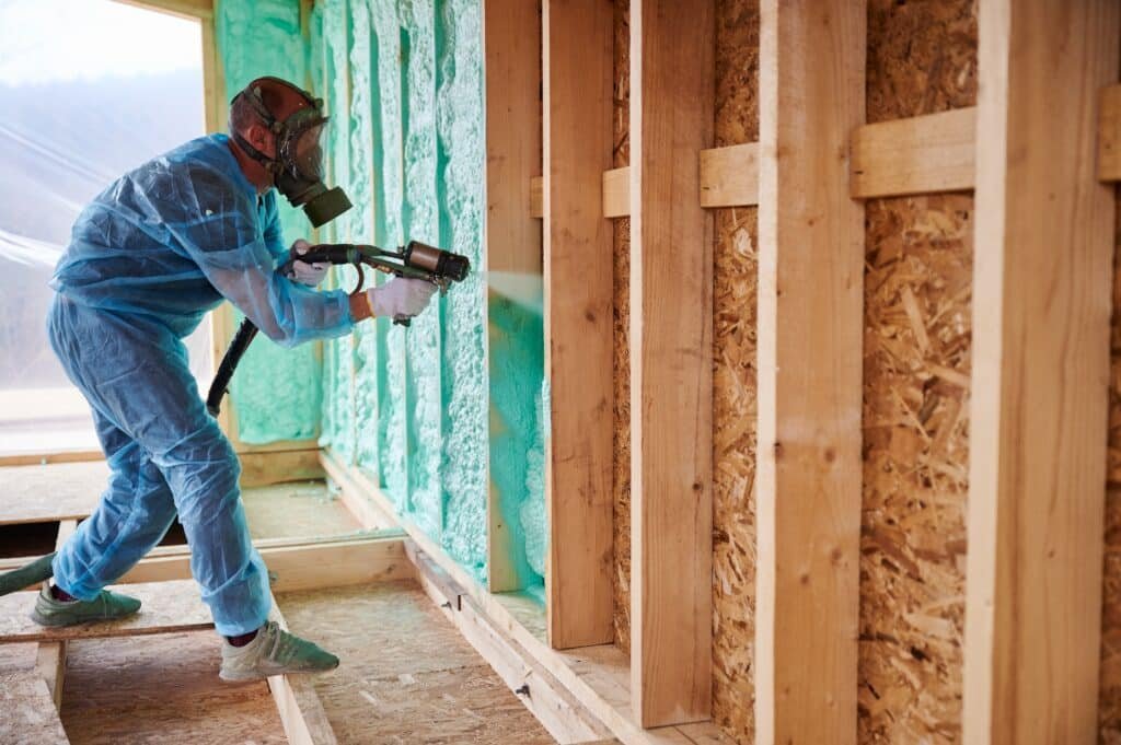 Worker spraying polyurethane foam insulation