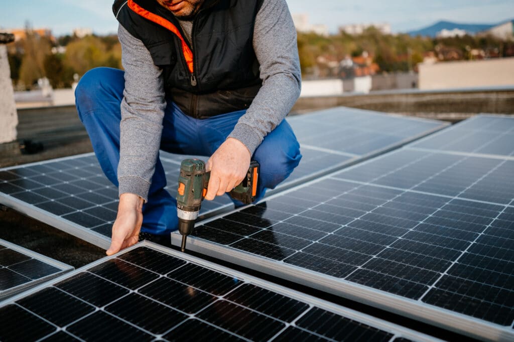 A man using a drill to install solar panels