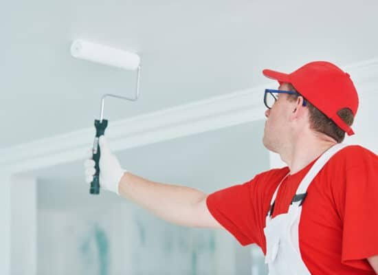Painter with roller painting ceiling