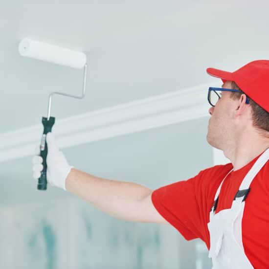Painter with roller painting ceiling
